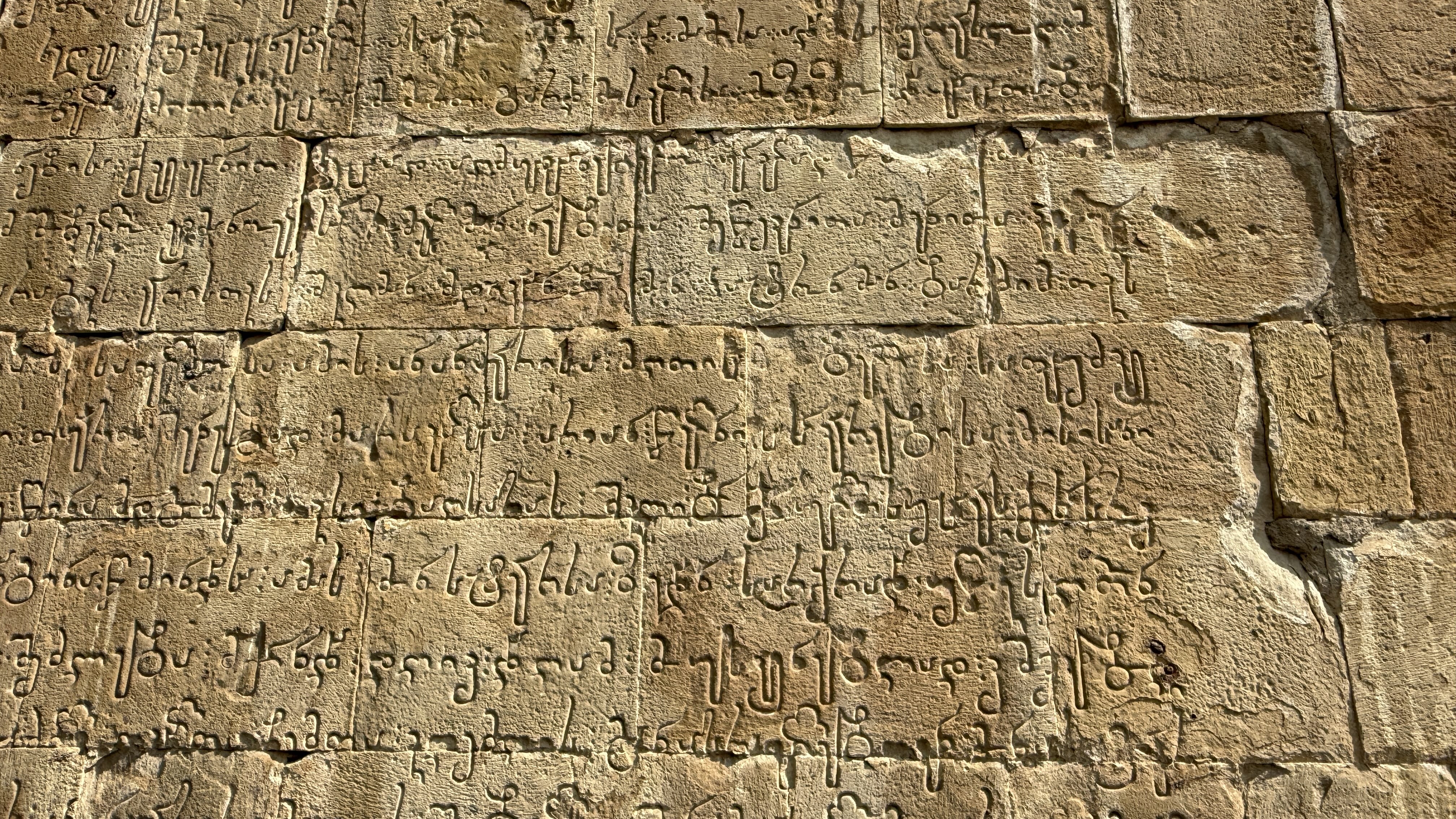 Close-up of medieval Georgian inscriptions carved into the stone walls of the church at Ananuri Fortress, Georgia.