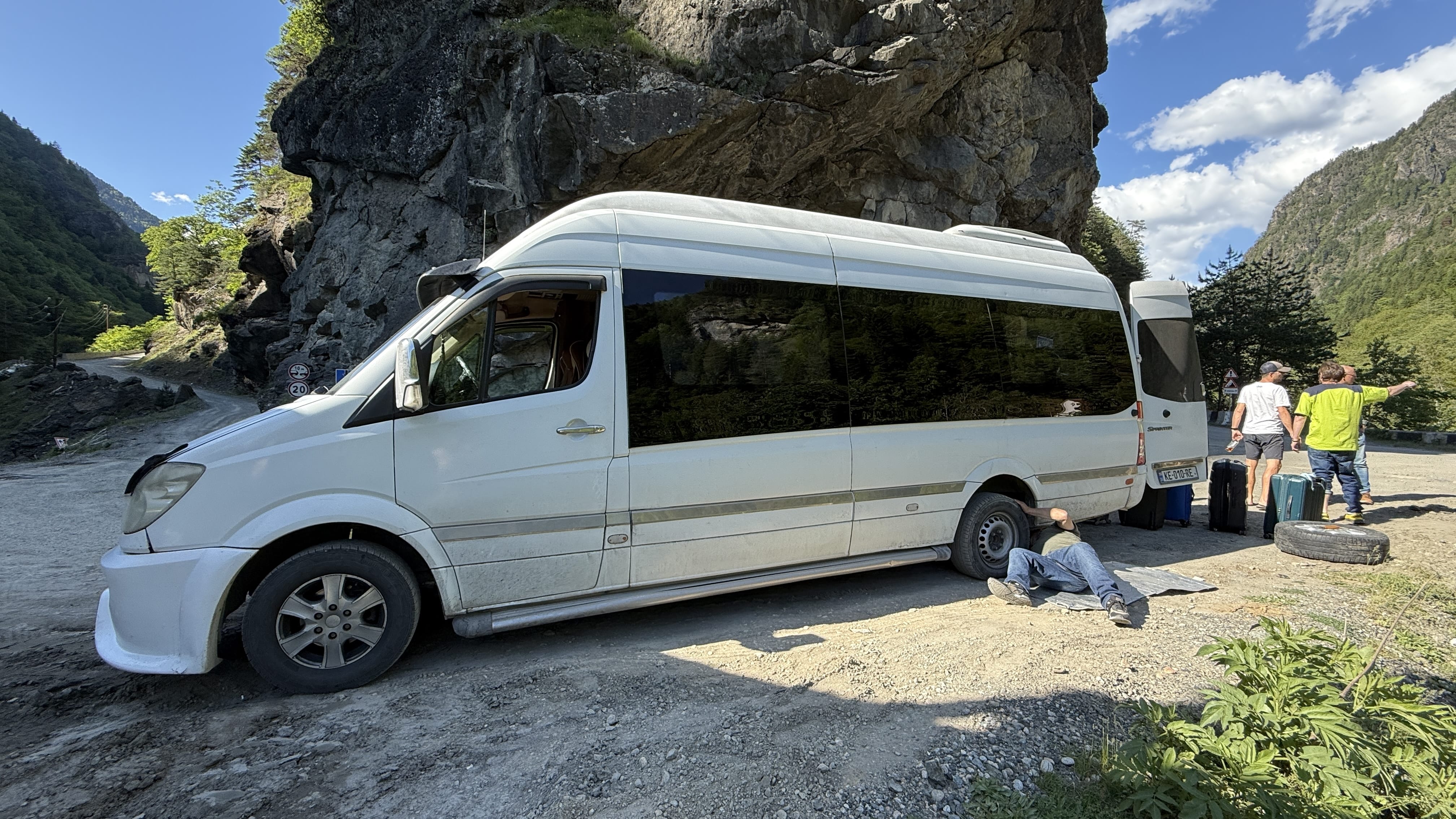 Minibus stopped on a mountain road with a flat tire during a road trip in Georgia’s Caucasus Mountains