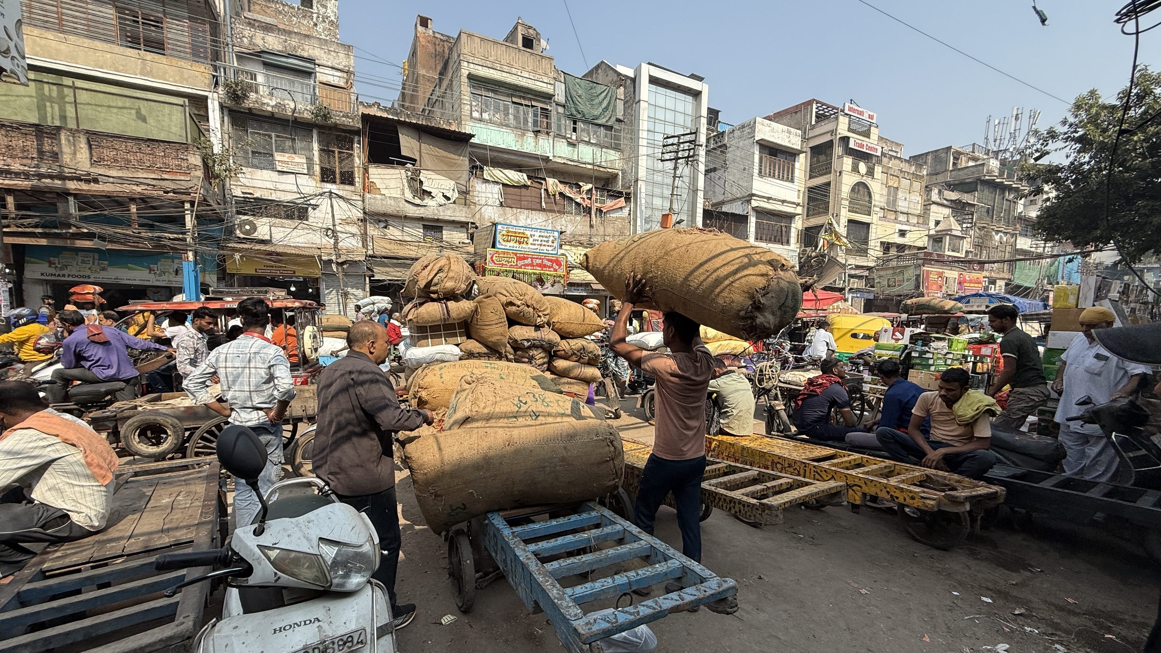 Workers loading market goods in Old Delhi during my 2 Days in Delhi itinerary, surrounded by carts, scooters, and historic storefronts.