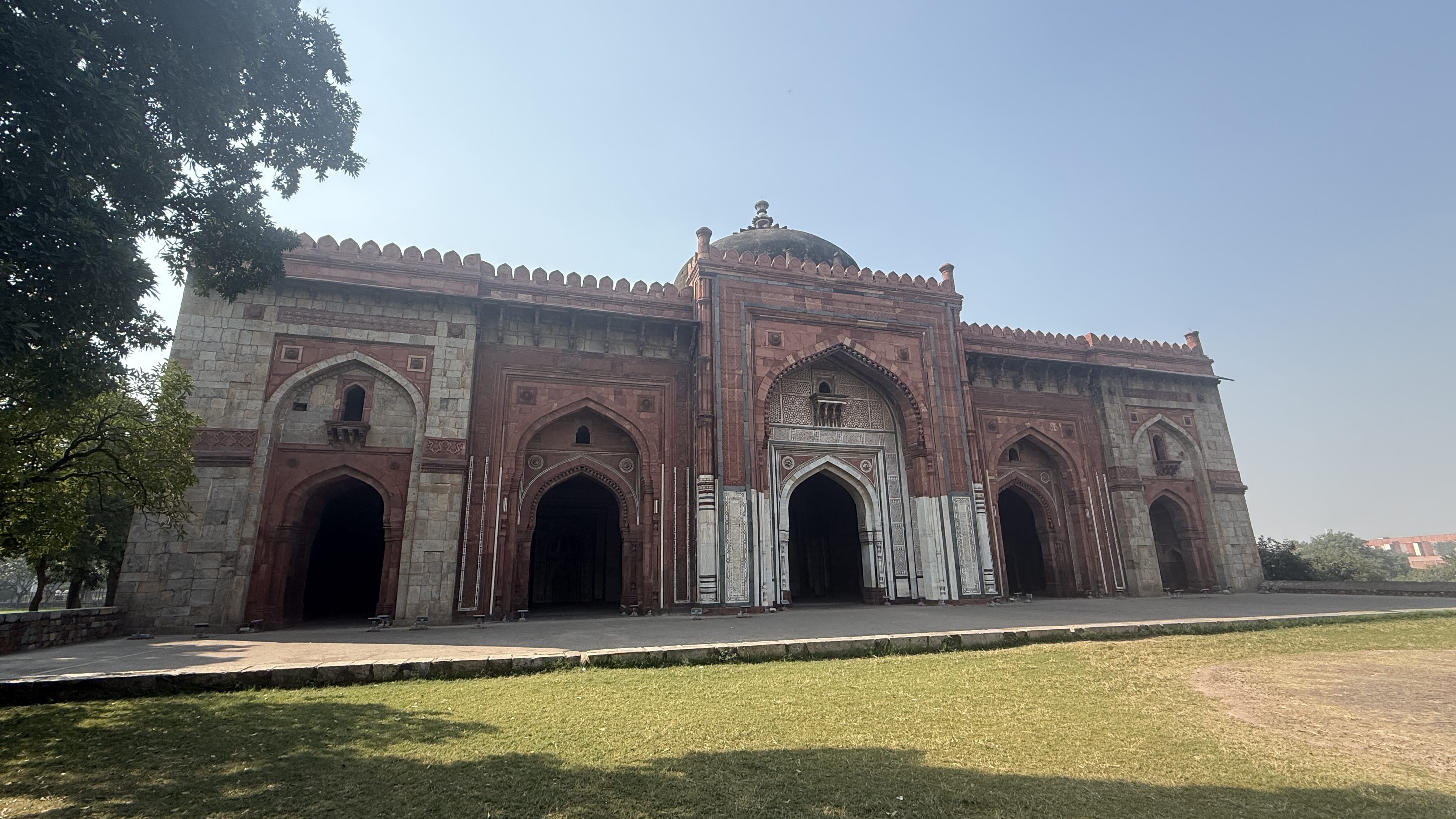 Exterior façade of the Qila-i-Kuhna Mosque at Purana Qila in Delhi, featuring red sandstone arches, white marble inlay, and a domed roof from the 16th-century Mughal period —2 Days in Delhi.