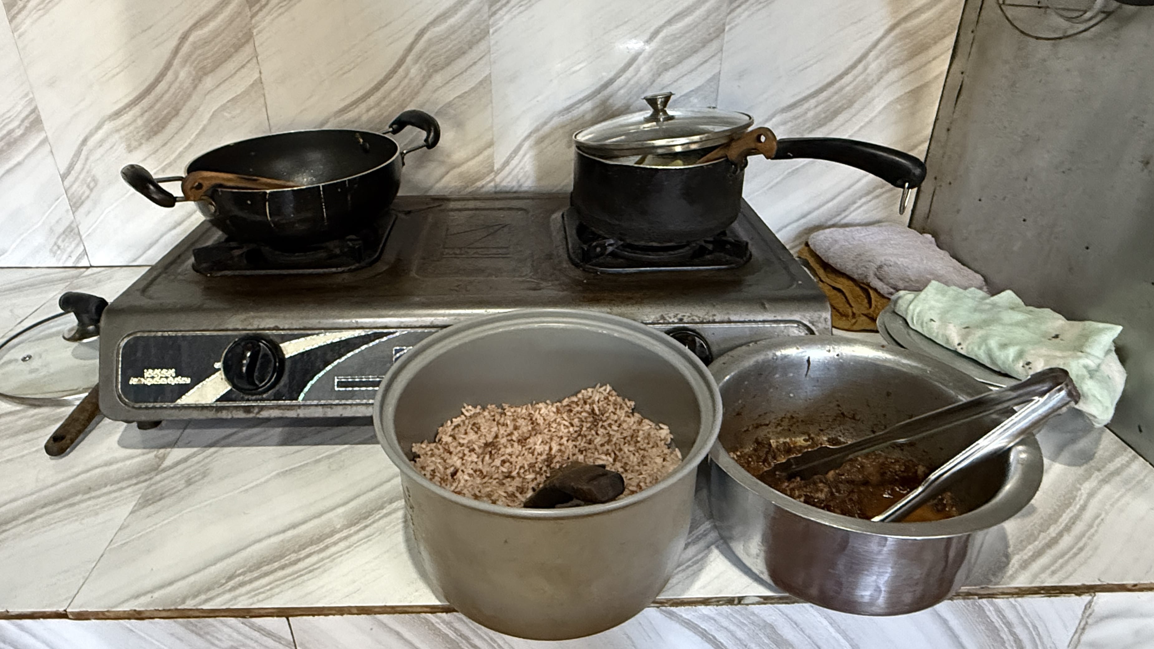 Simple stove and home-cooked meal in a guesthouse kitchen in Haa Valley, Bhutan, with pots of red rice and curry prepared on a basic two-burner stove.