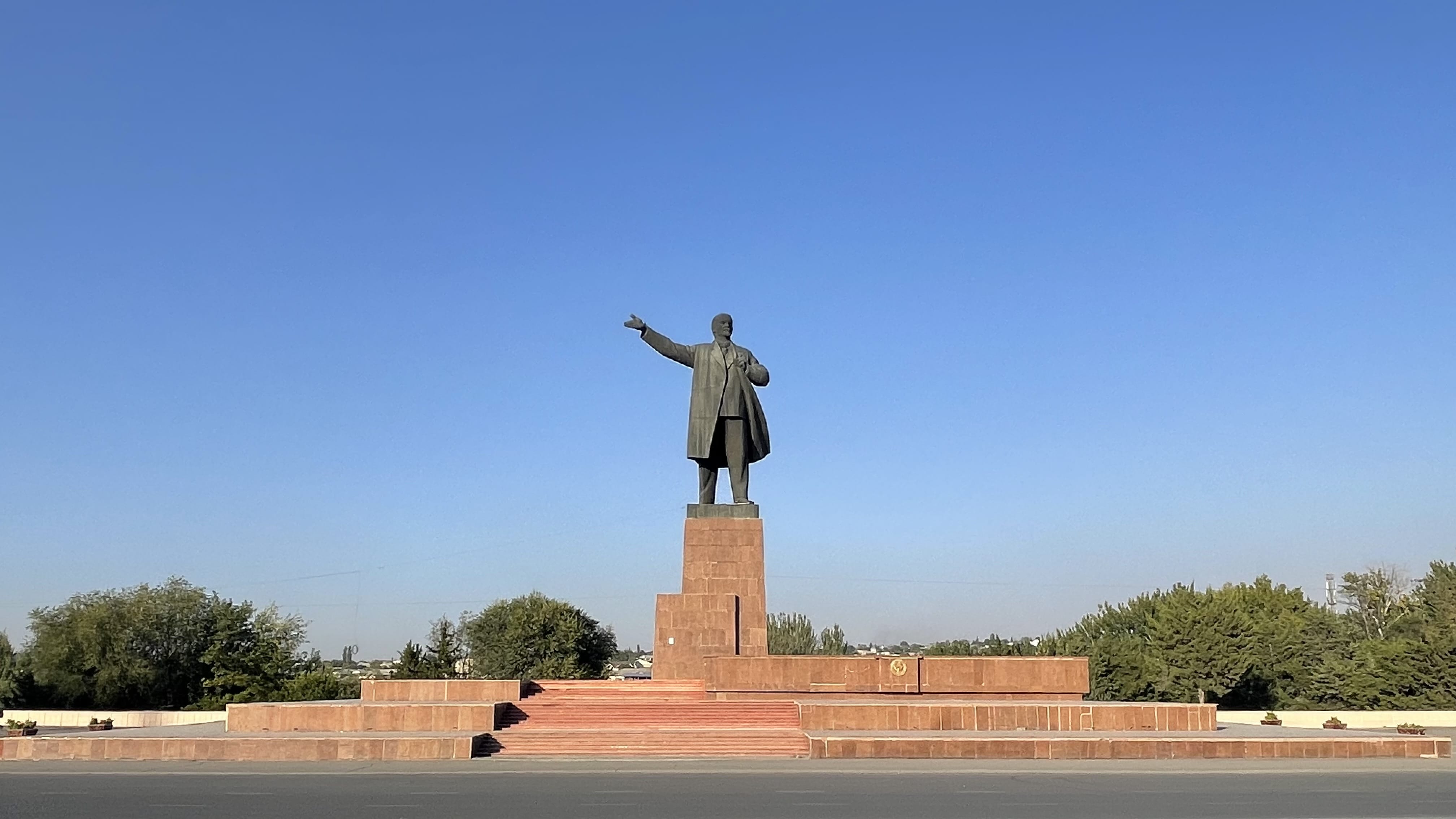 Massive Lenin statue in Osh, Kyrgyzstan, standing in the city center against a clear blue sky.