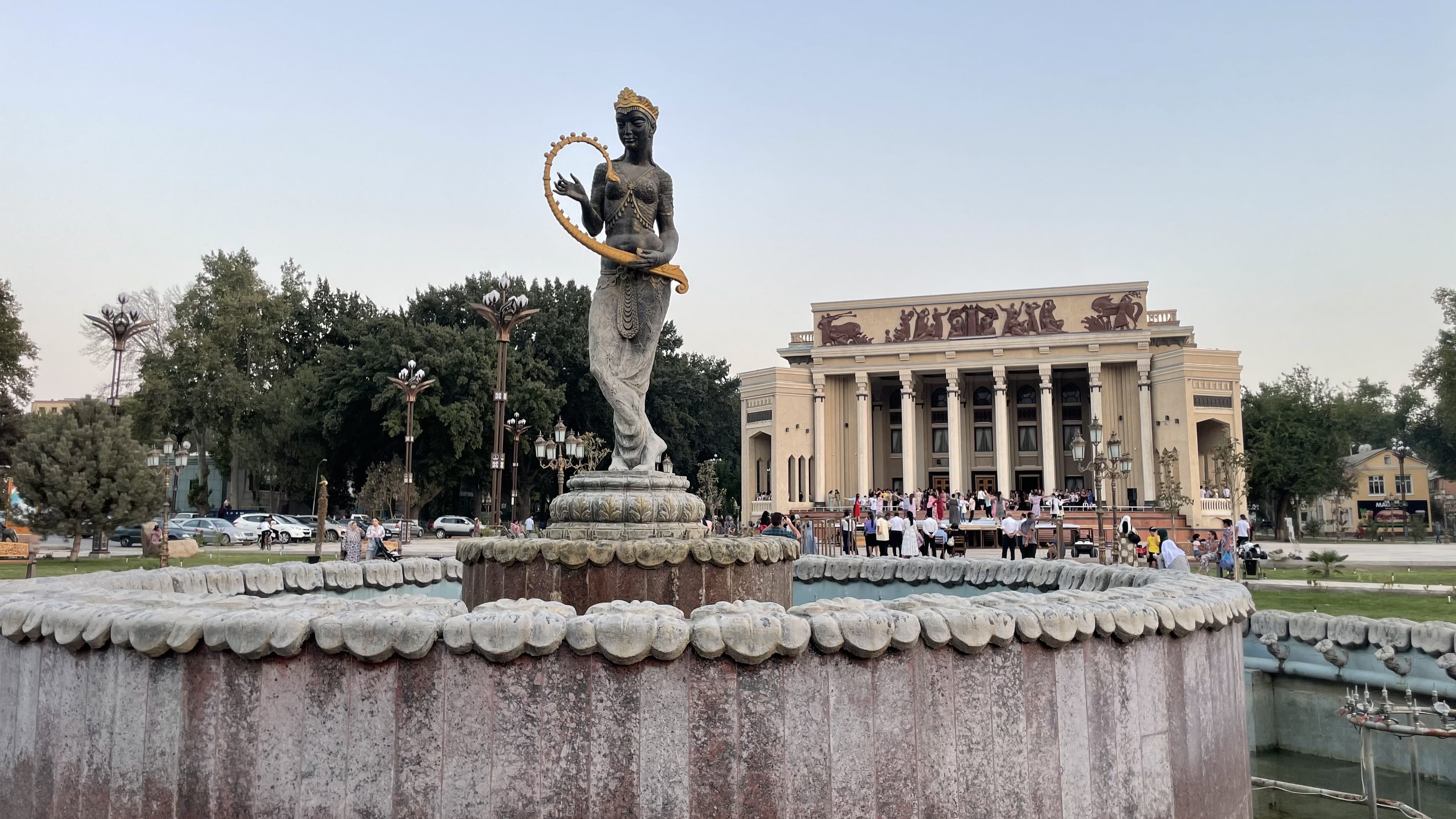 People gathered in front of the Khujand Fortress Museum in Khujand, Tajikistan, watching dancers perform under a covered platform in the main square during the evening during our 3 days in Khujand, Tajikistan.