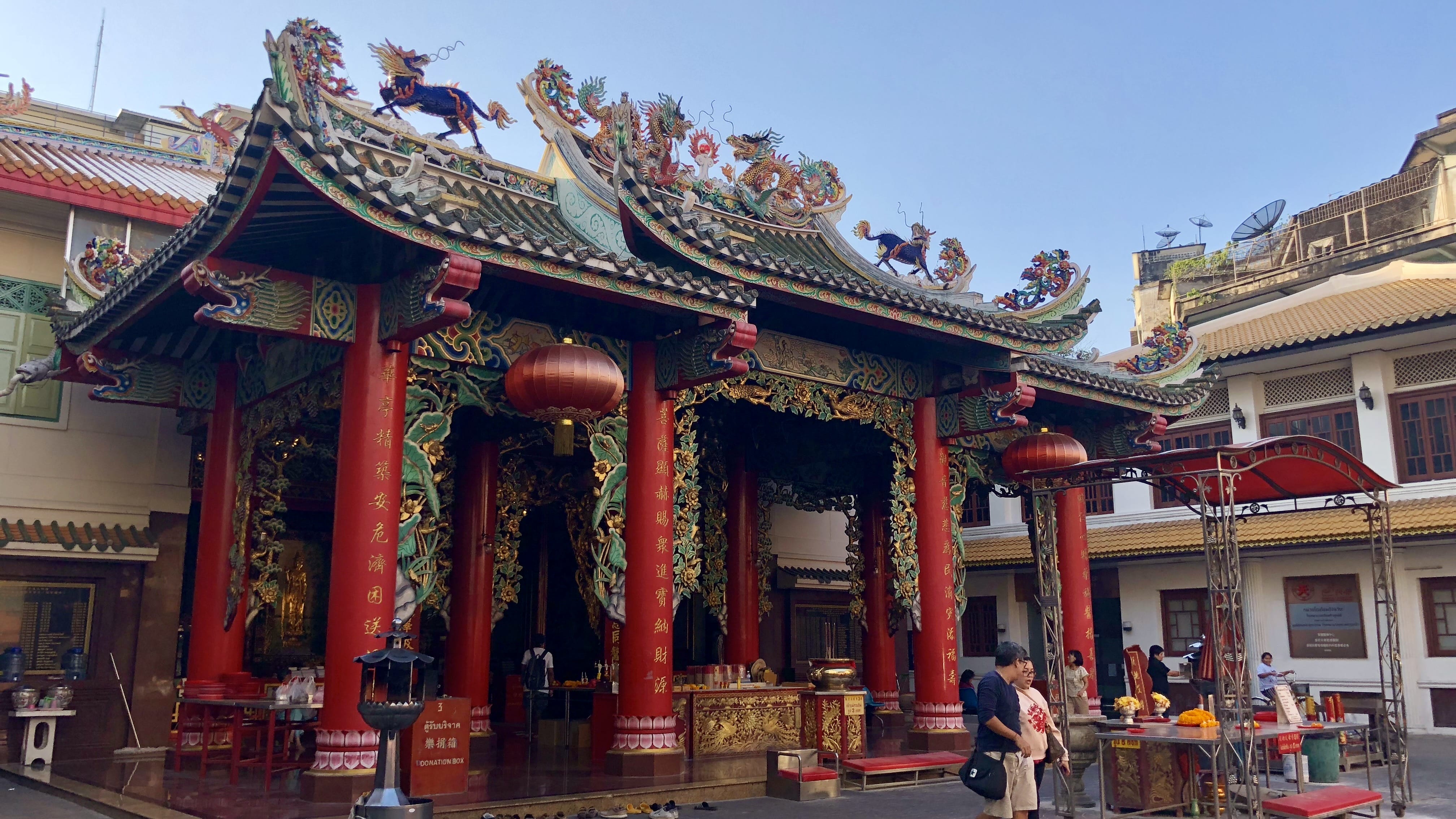 Exterior of Leng Noei Yi Shrine, a historic Taoist temple in Bangkok with red columns, carved dragons, and hanging lanterns