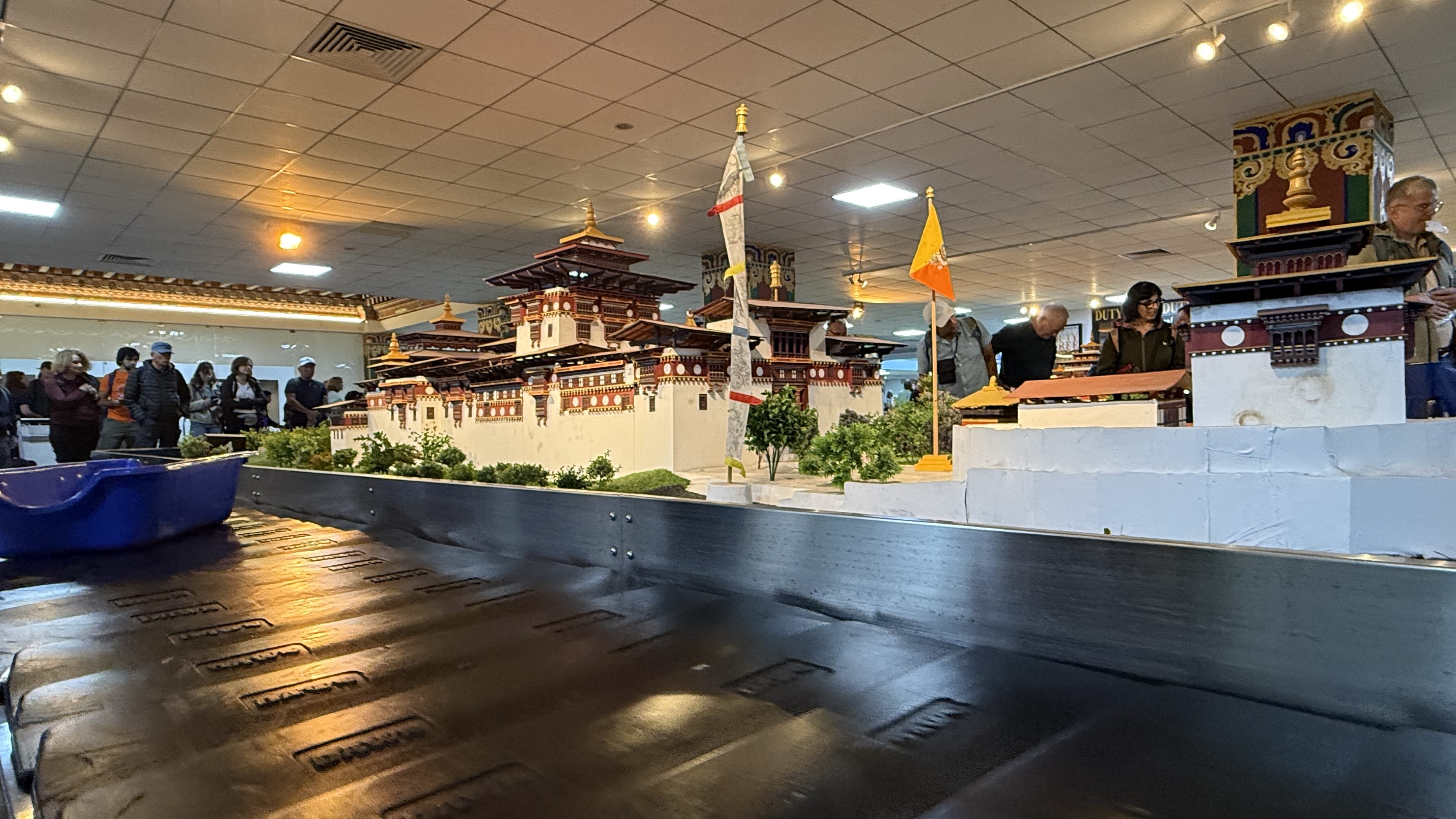 Baggage carousel at Paro Airport in Bhutan featuring a miniature dzong and traditional Bhutanese architecture