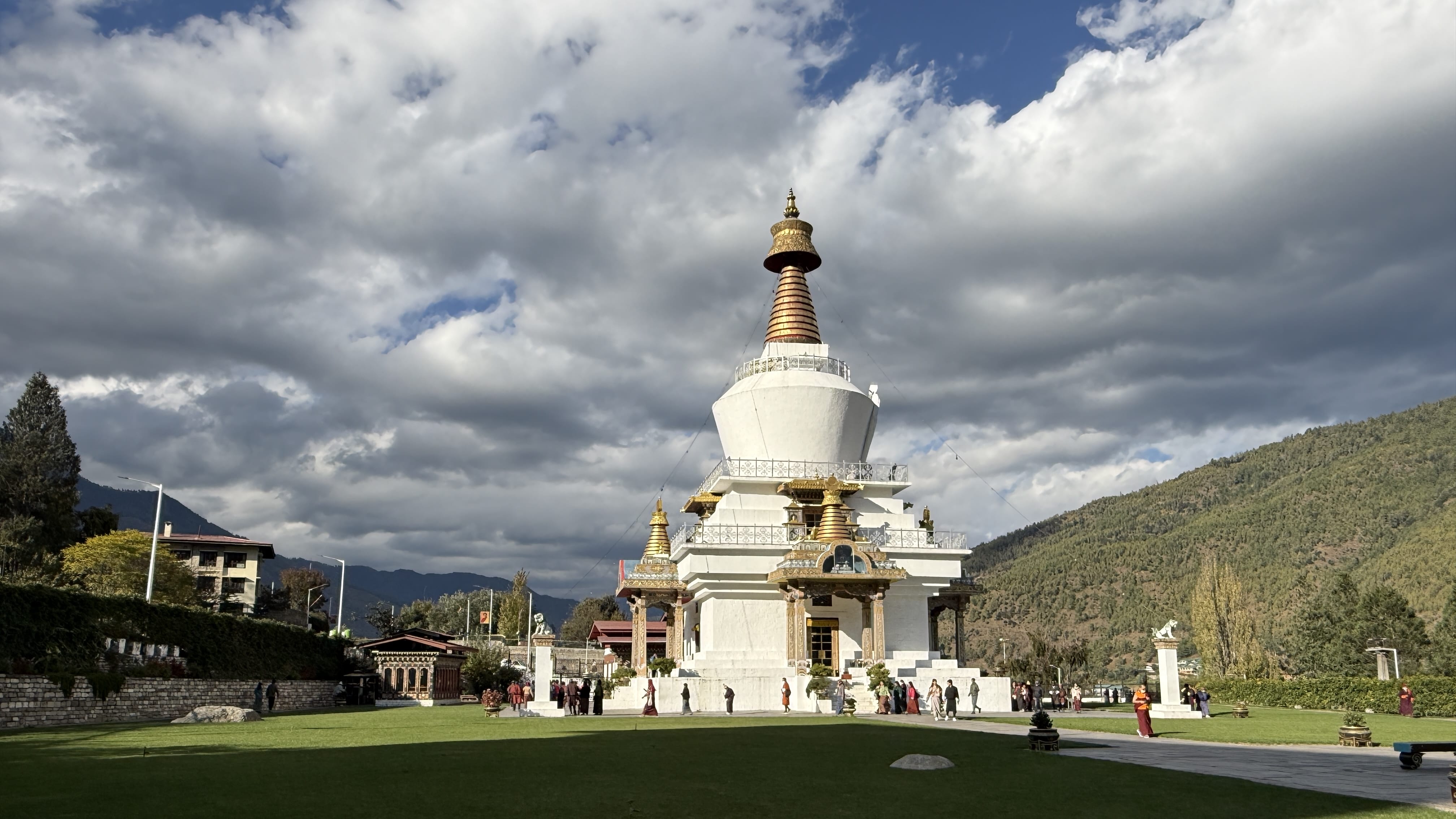 National Memorial Chorten with whitewashed stupa and golden spire, surrounded by prayer wheels and visitors walking the circumambulation path.