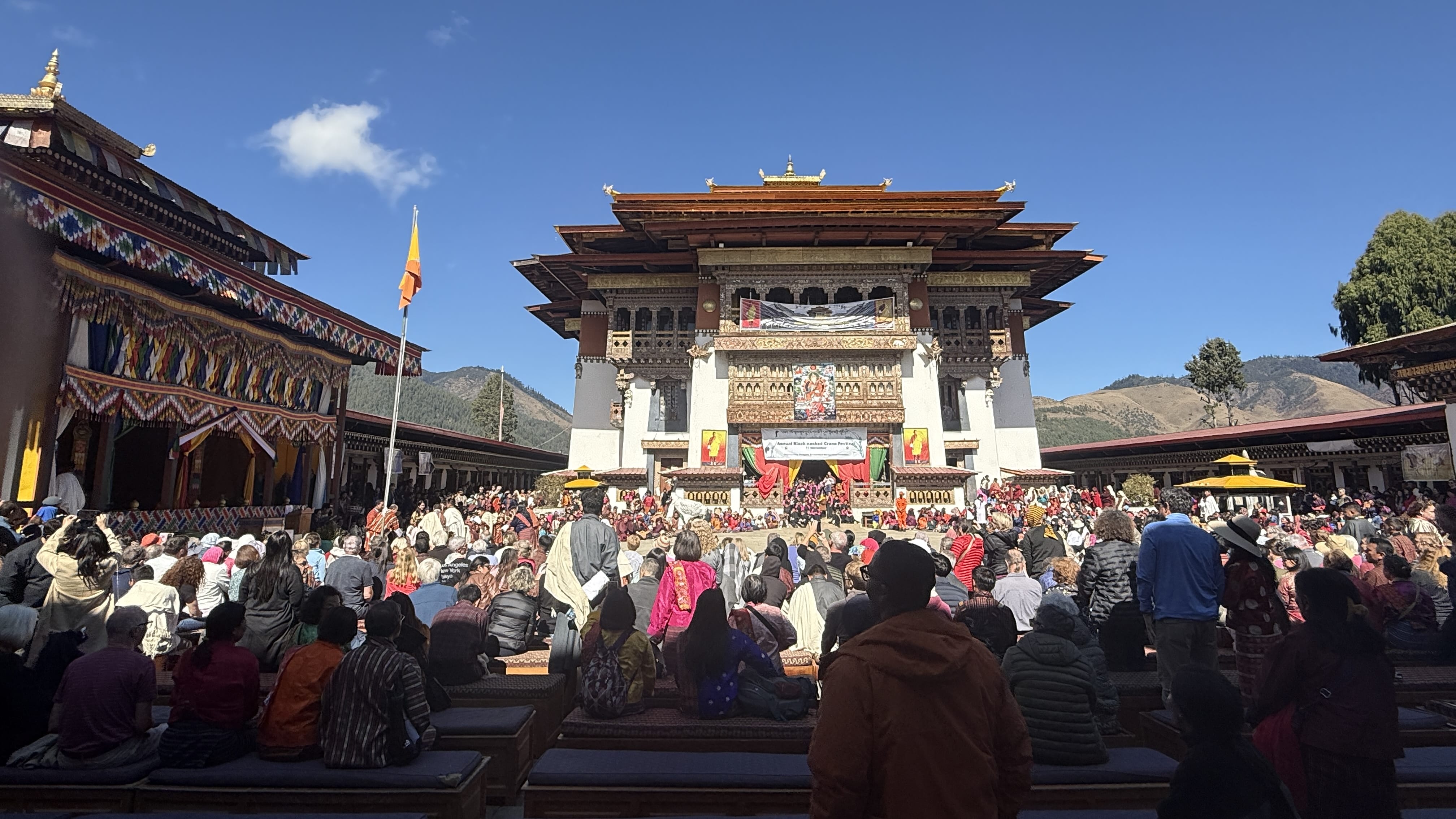 11 Days in Bhutan: crowd gathered in the courtyard at Gangtey Monastery in Phobjikha Valley during the Black-necked Crane Festival, with a crane statue in the center.