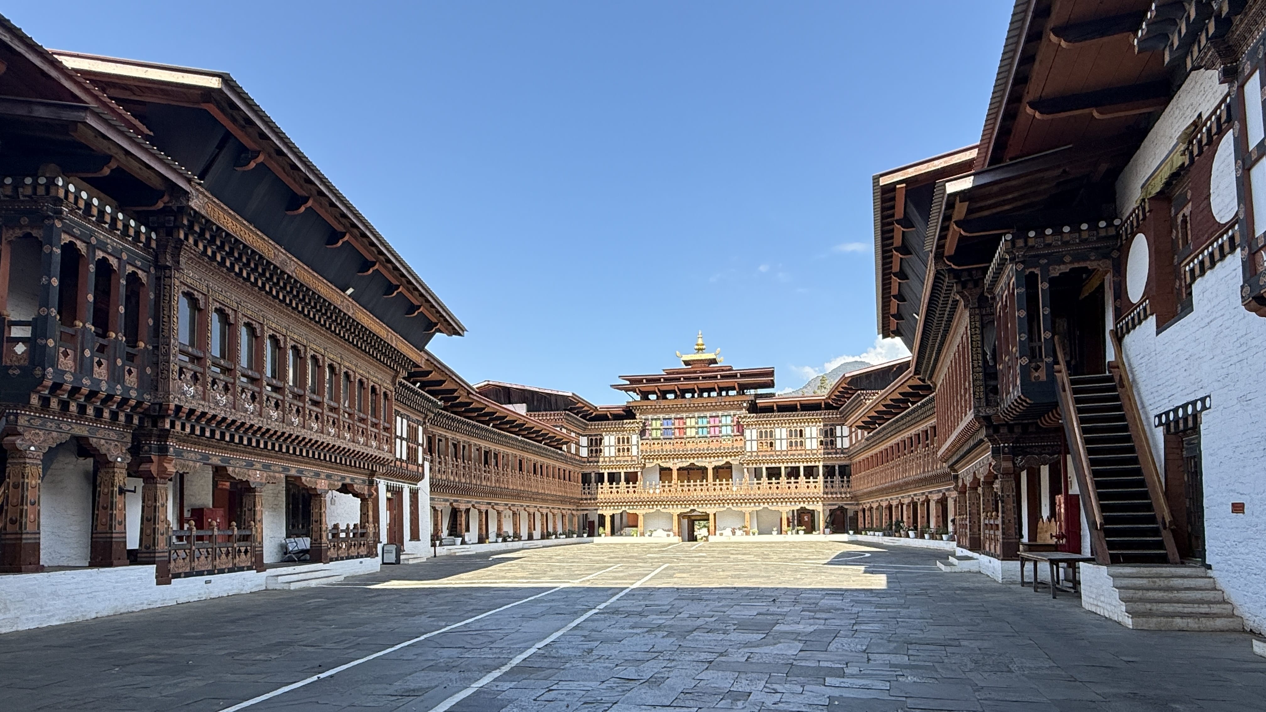 11 Days in Bhutan: wide courtyard at Wangdue Phodrang Dzong with traditional Bhutanese wooden balconies, whitewashed walls, and the central tower under a blue sky.