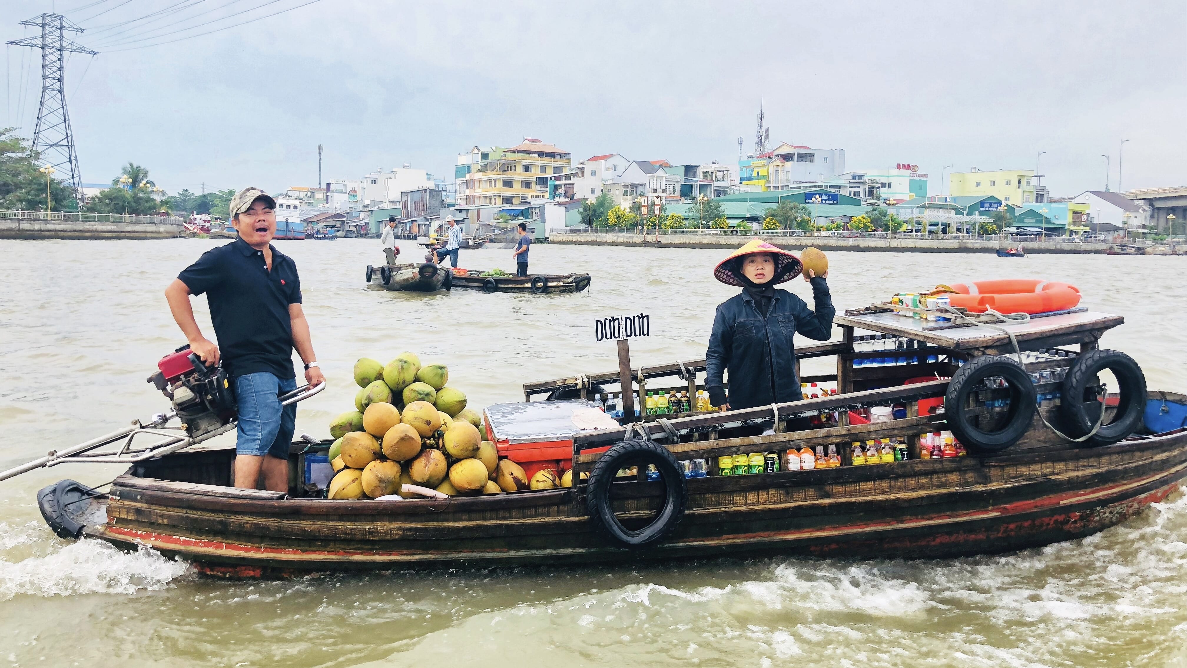 Floating market vendors selling coconuts from wooden boats in the Mekong Delta
