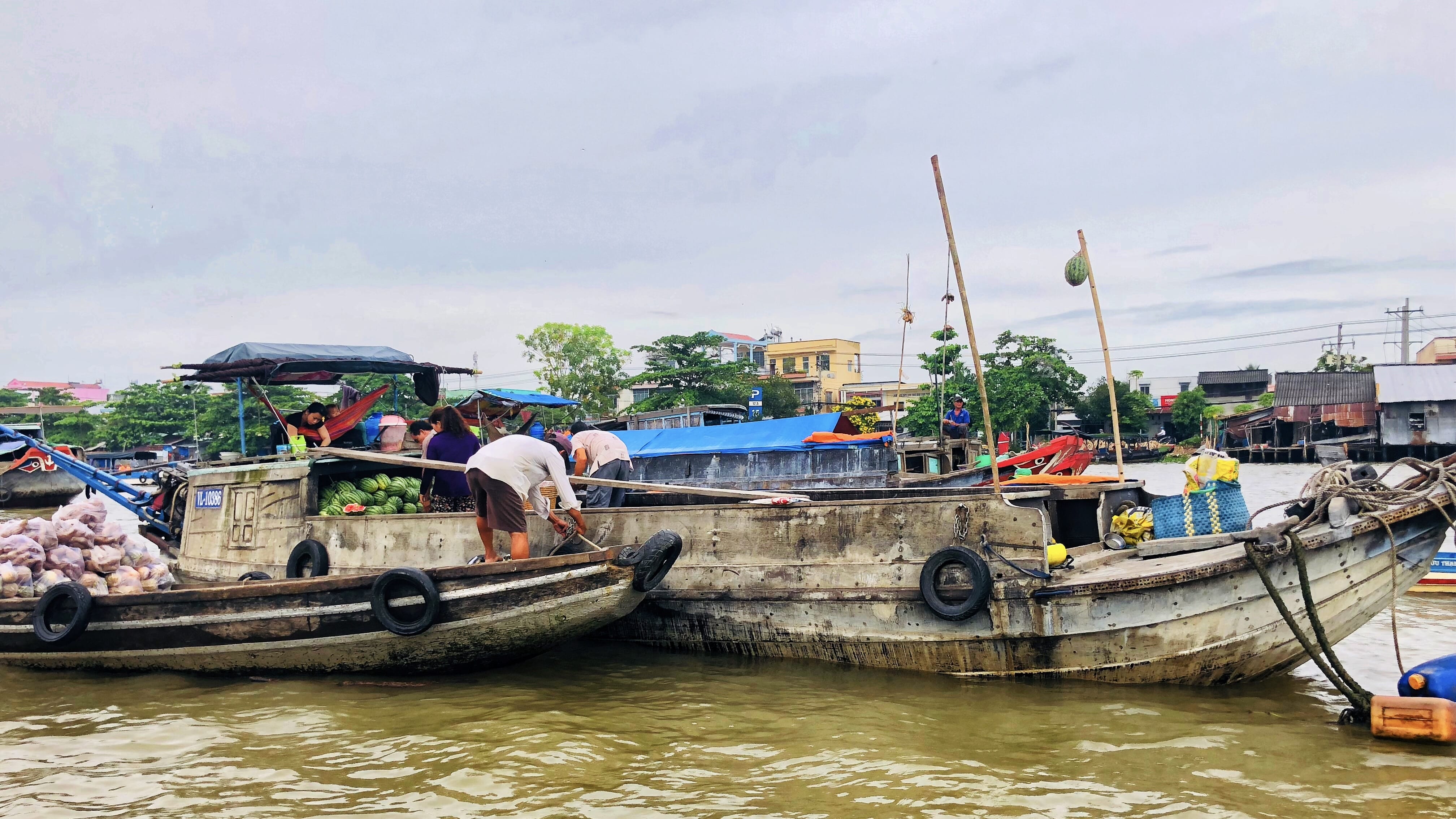 Vendors transferring produce between boats at Mekong Delta floating market during six days in Vietnam