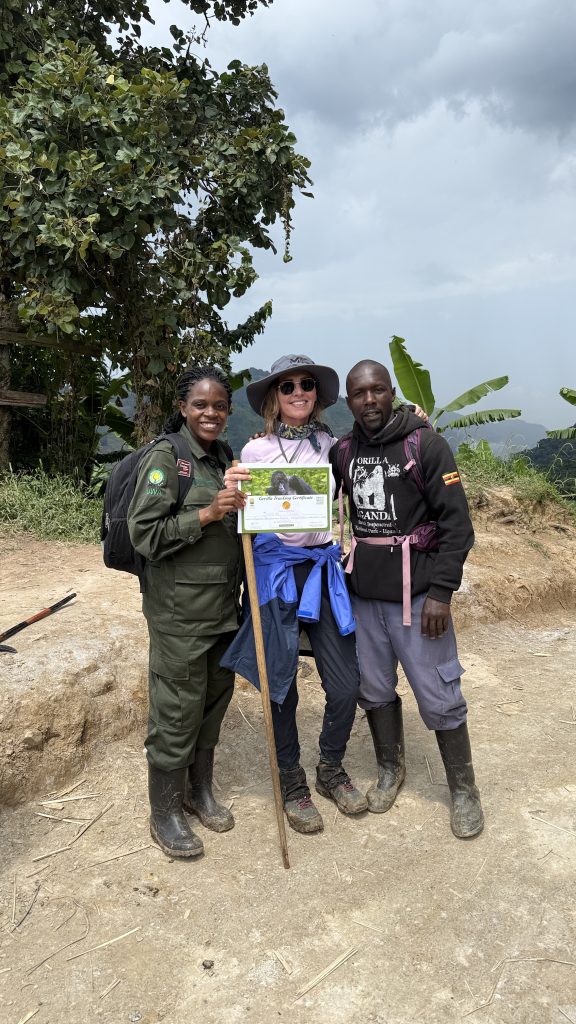 Traveler holding gorilla trekking certificate with Uganda Wildlife Authority ranger and guide in Bwindi