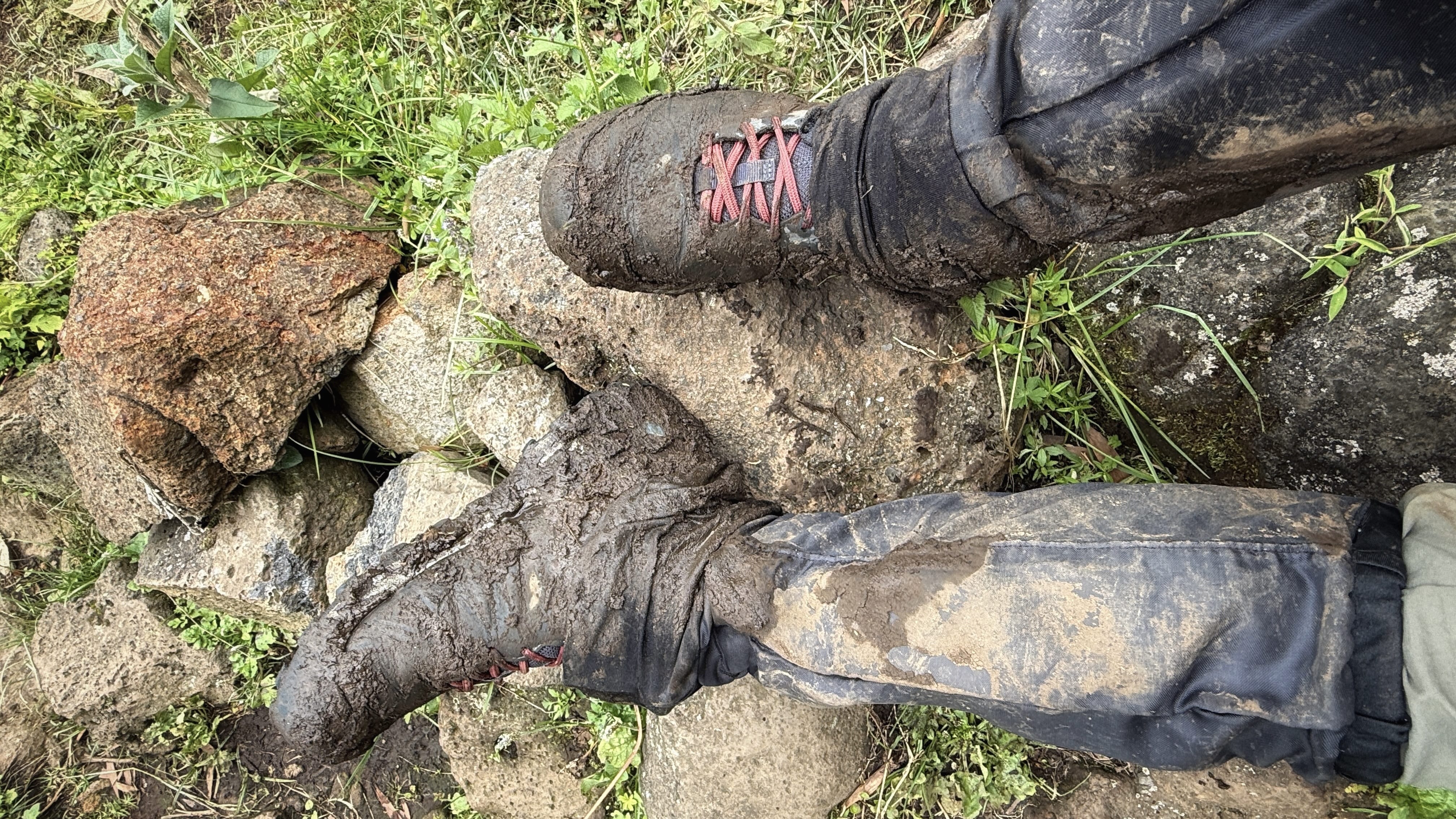 Mud-covered hiking boots and pants after the Dian Fossey hike in Volcanoes National Park, Rwanda.