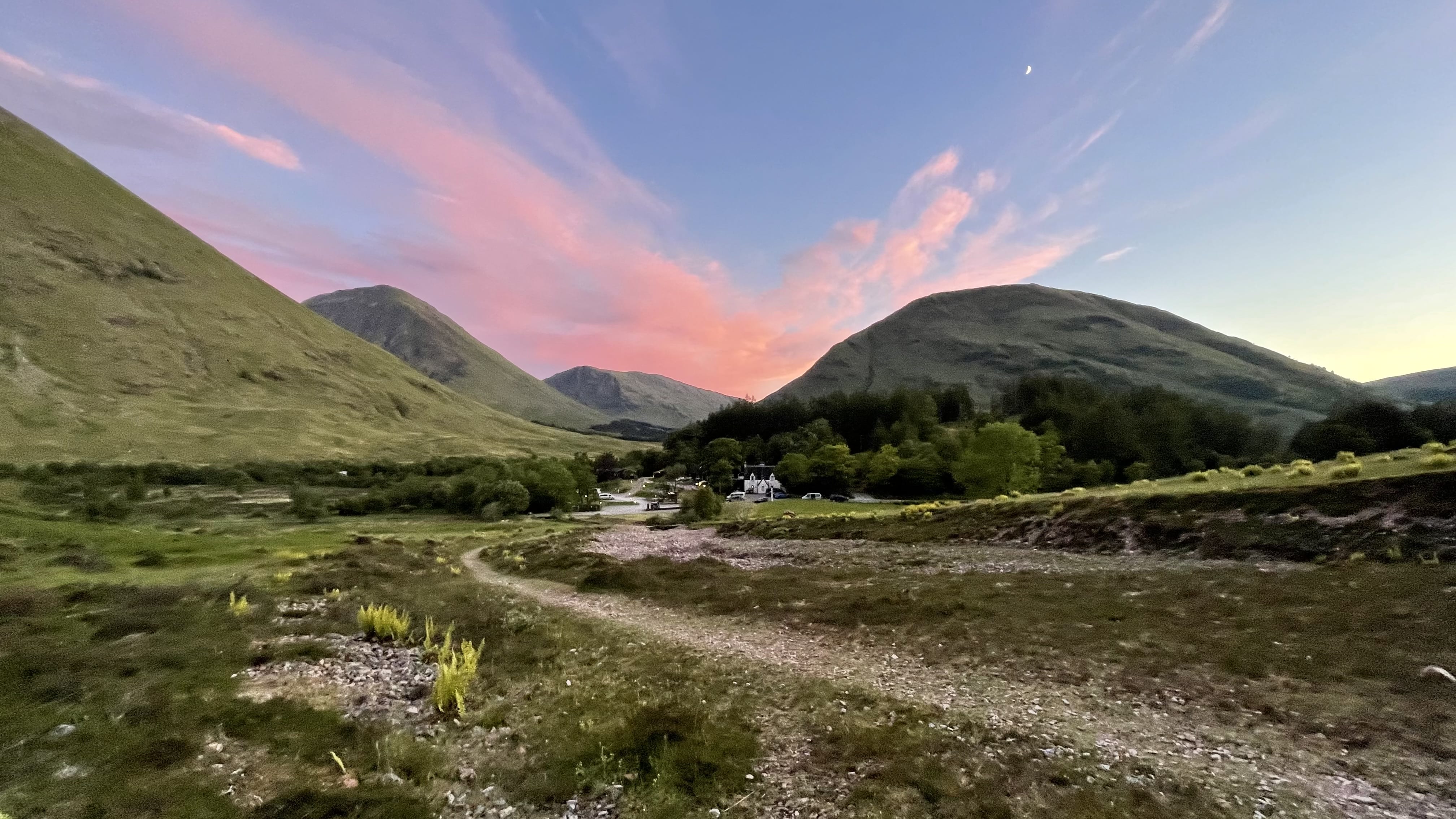 Glencoe Scotland sunset at 10:30 pm with pink clouds over Highland mountains and winding path through valley