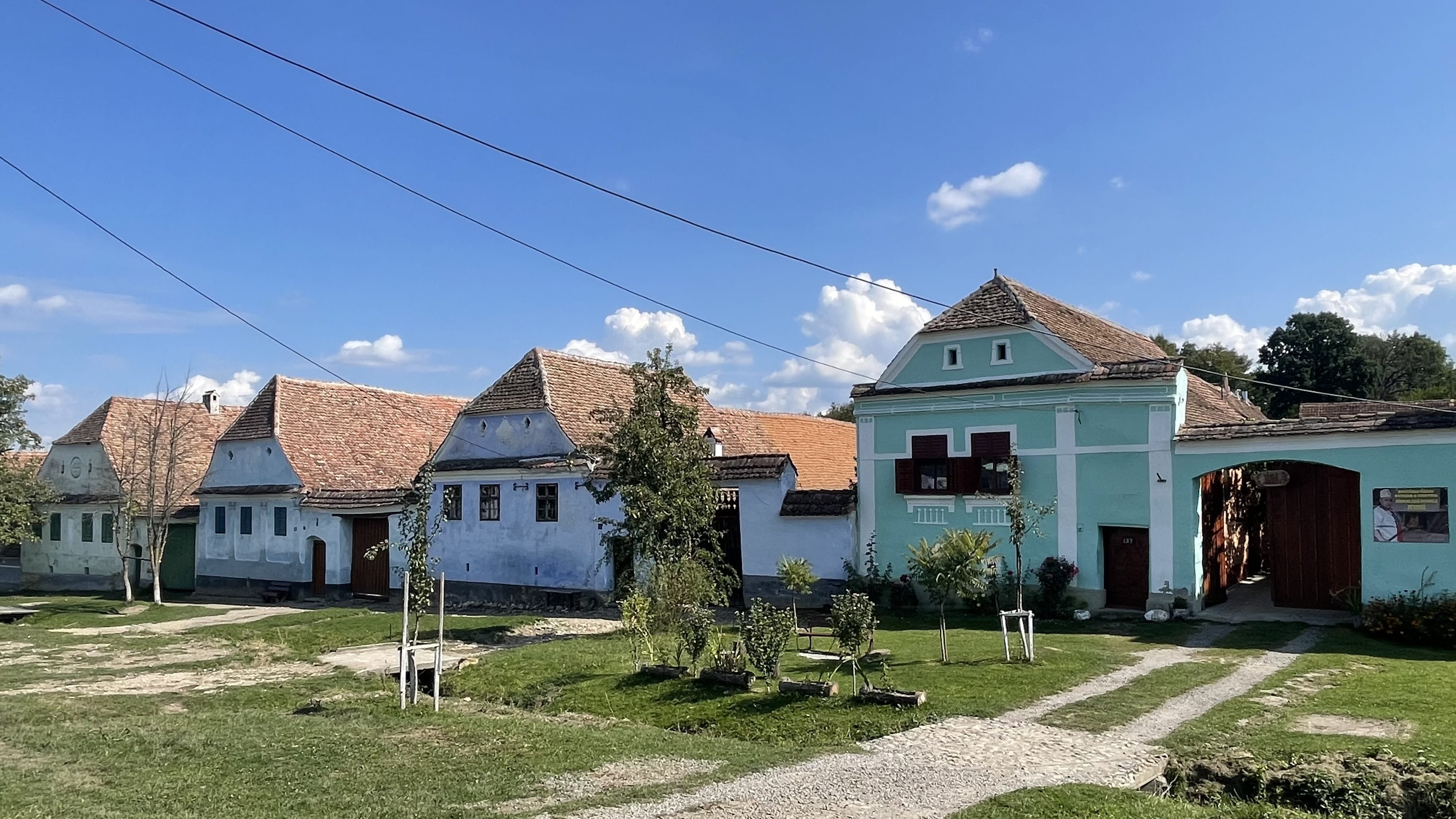 Blue Saxon house with wooden gate and green shutters in Viscri, Romania.