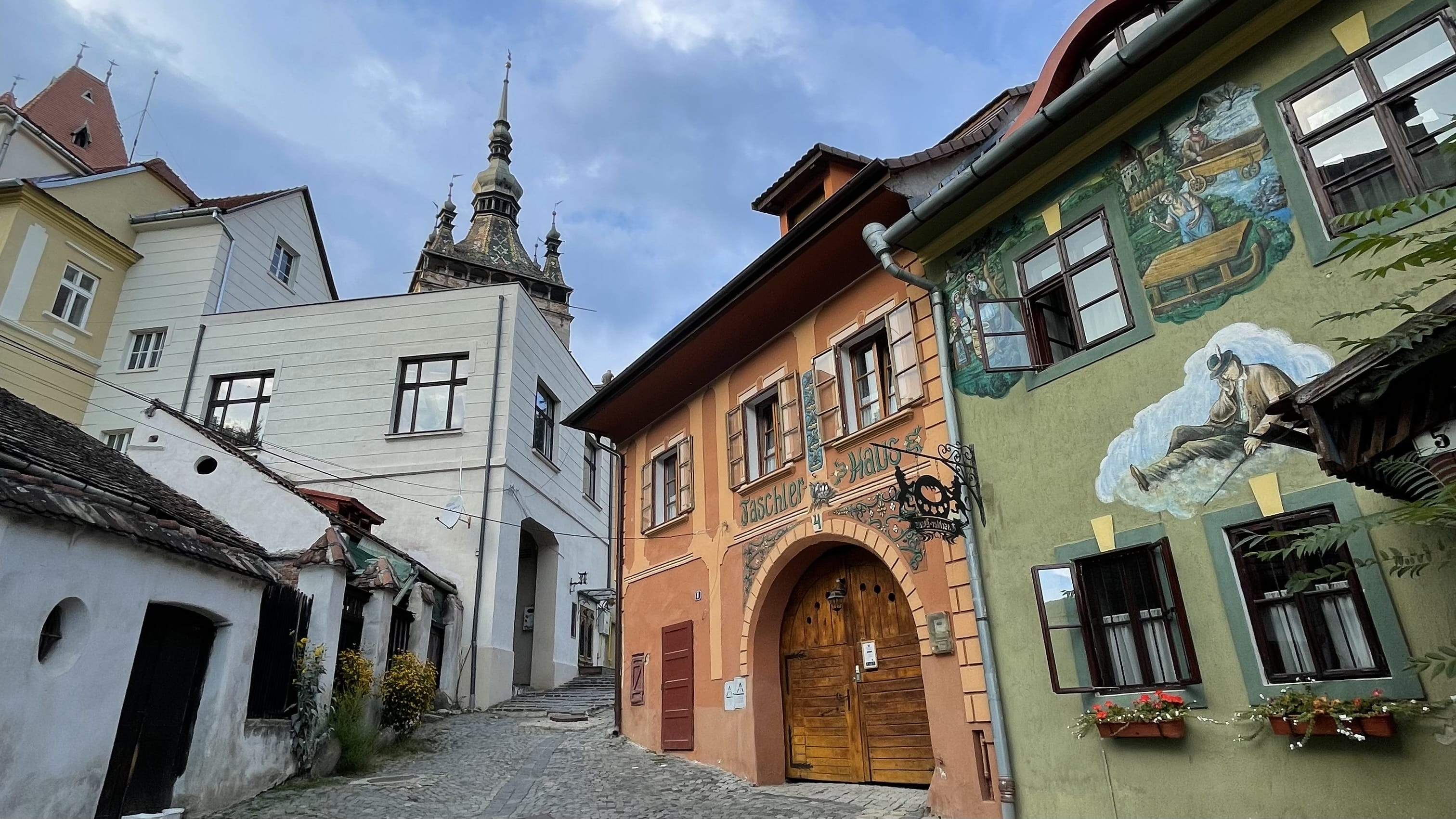 Colorful historic buildings along a cobblestone street in Sighișoara, Romania.