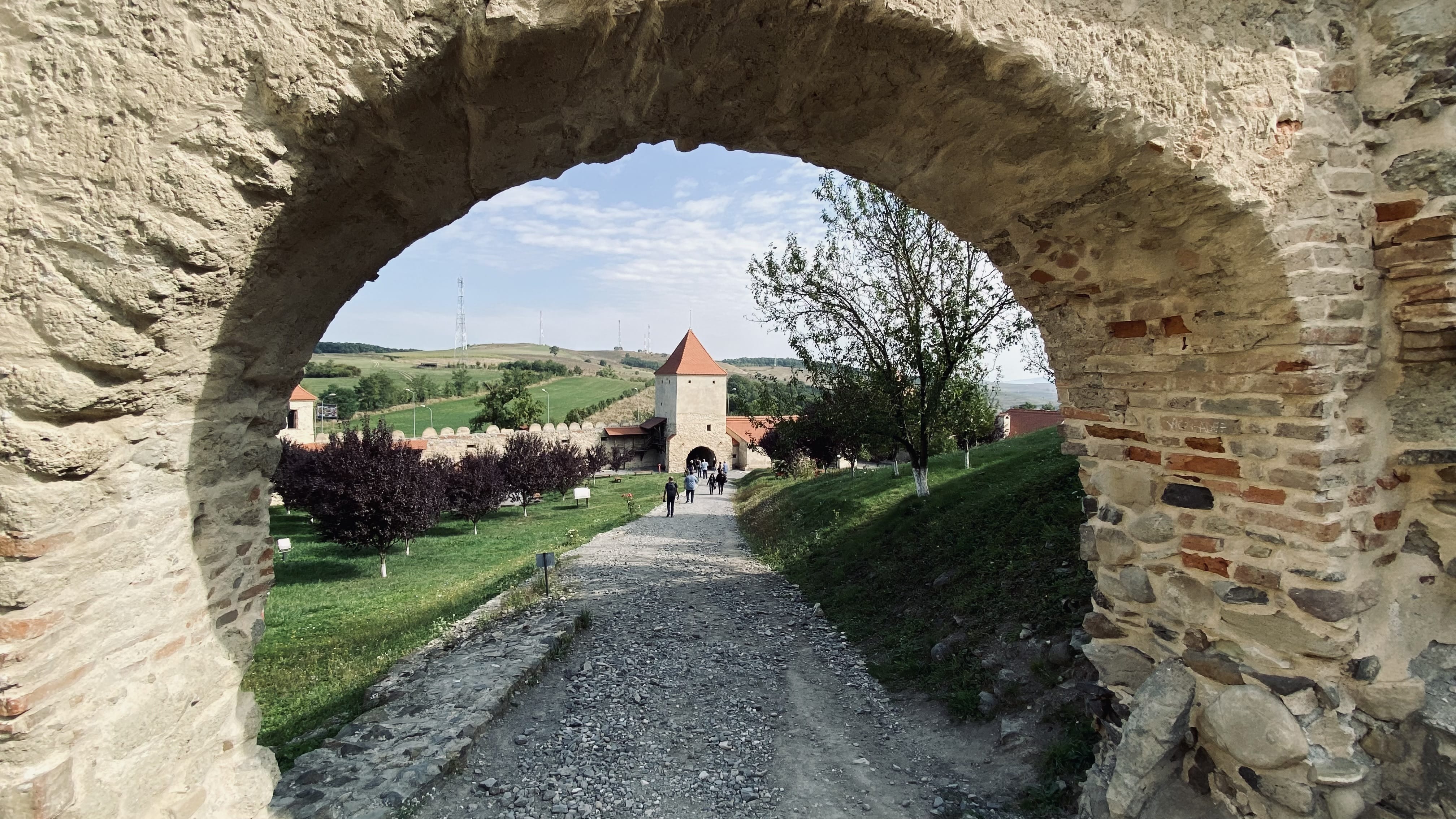 View through a stone archway toward towers and walls at Rupea Citadel, Romania.