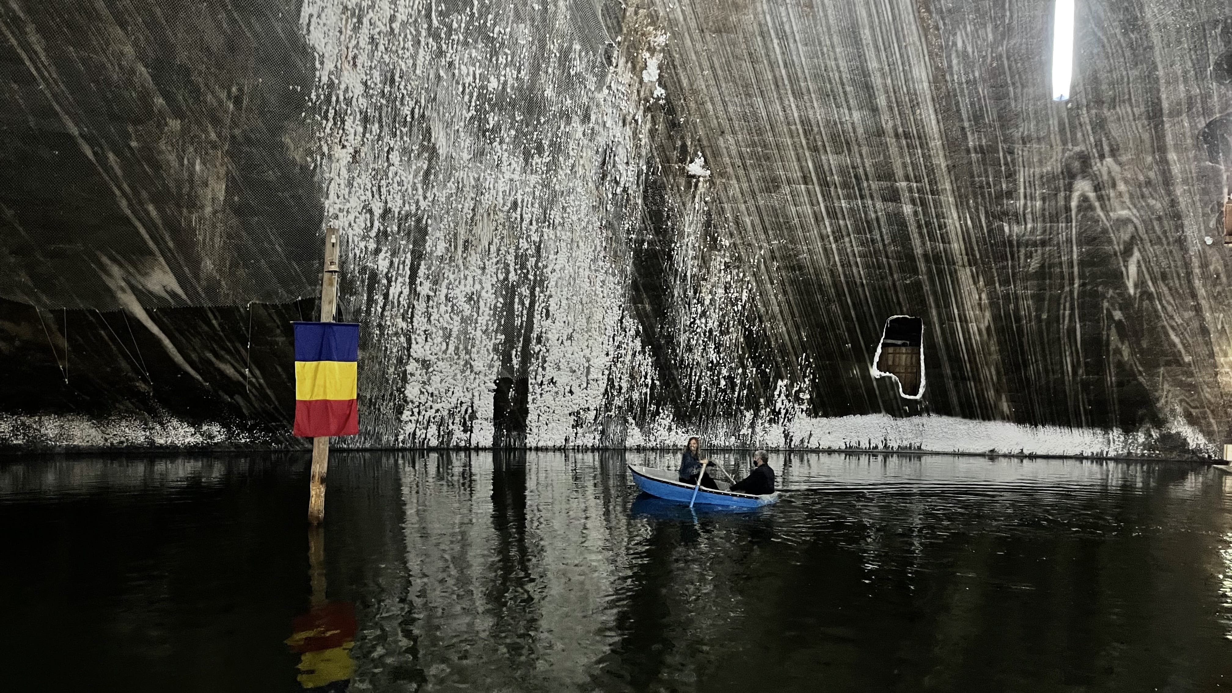 Visitors rowing boats on the underground lake inside Salina Turda salt mine, Romania.