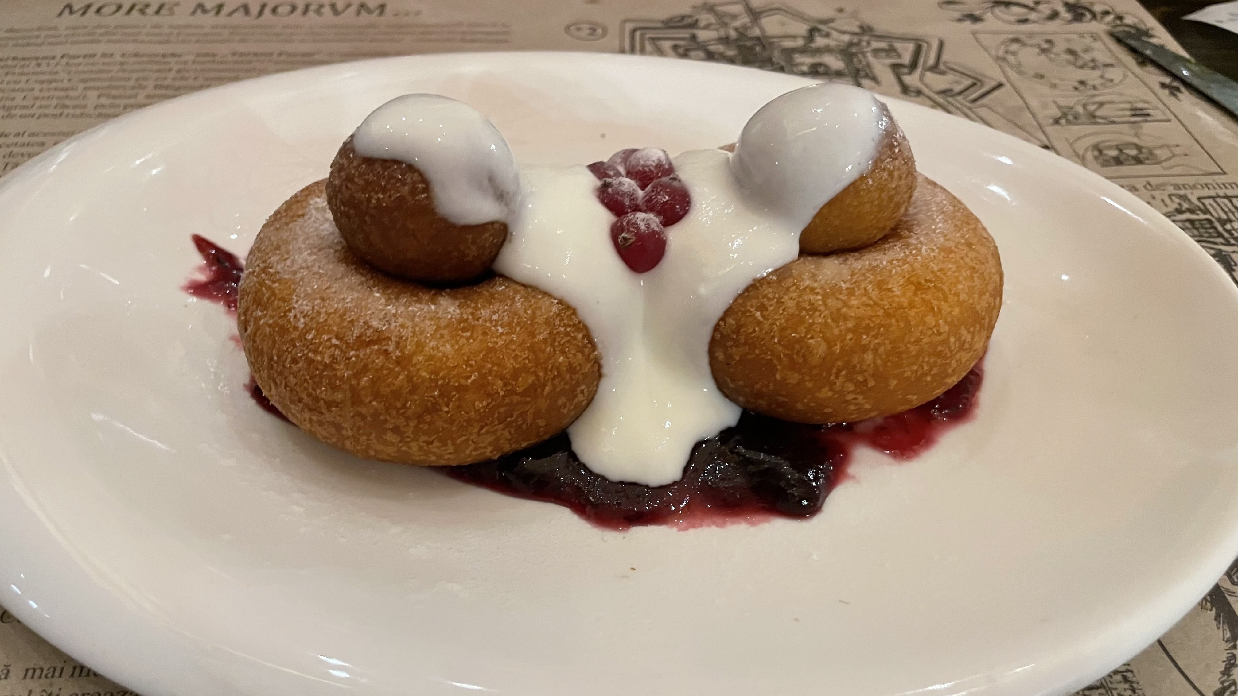 Traditional Romanian papanași dessert topped with sour cream and berry jam.