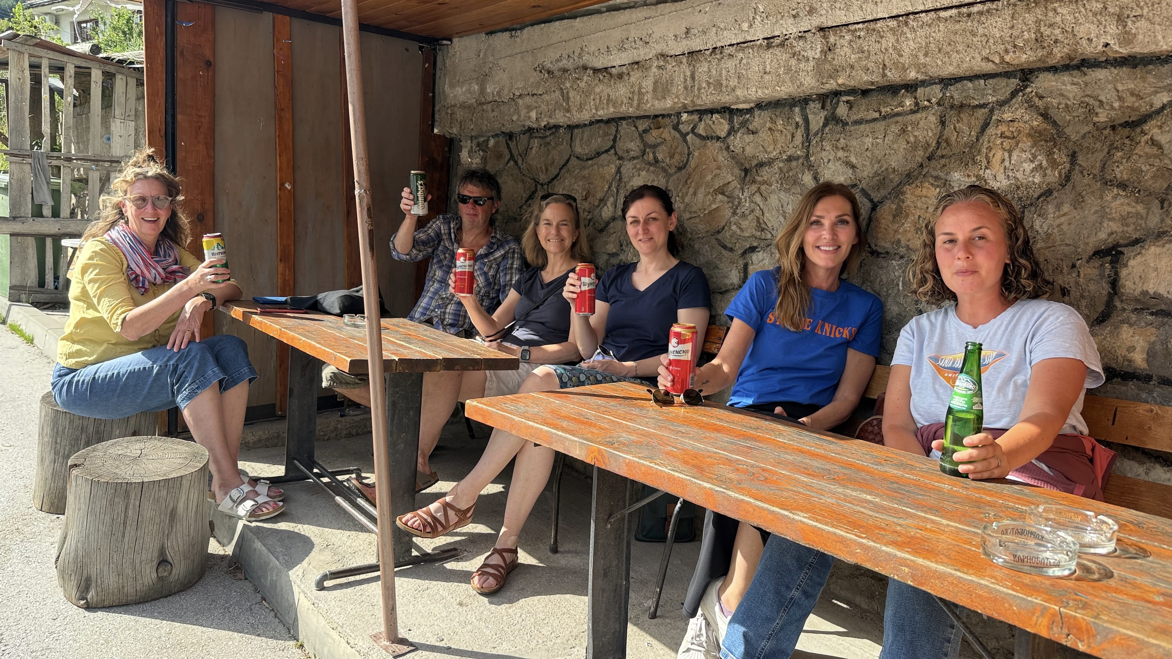 Group of hikers sitting outside a small village grocery store and bar in Yagodina, Bulgaria, drinking beer after a day of hiking.