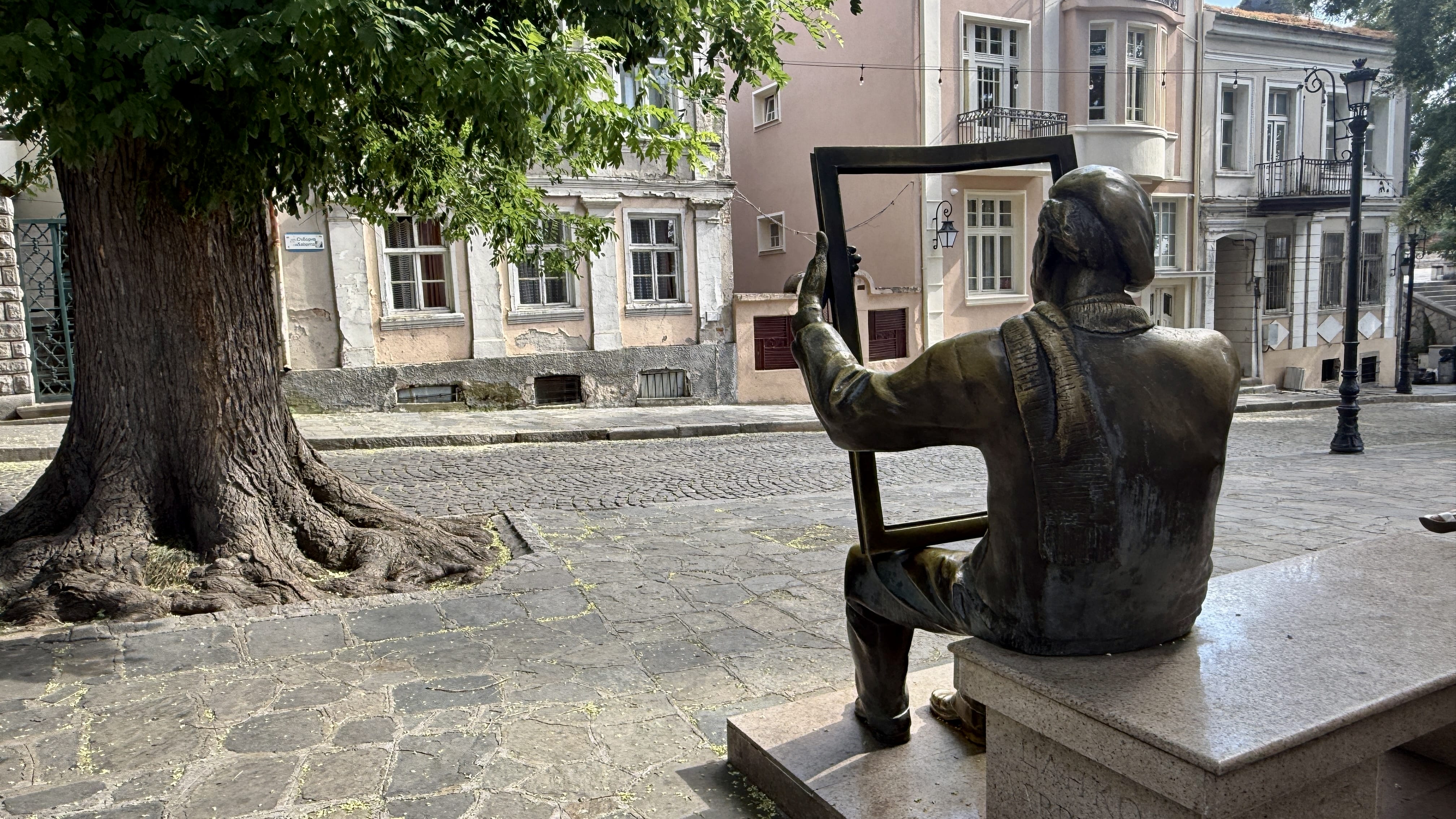 Statue of an artist holding an empty picture frame on a cobblestone street in Plovdiv, Bulgaria
