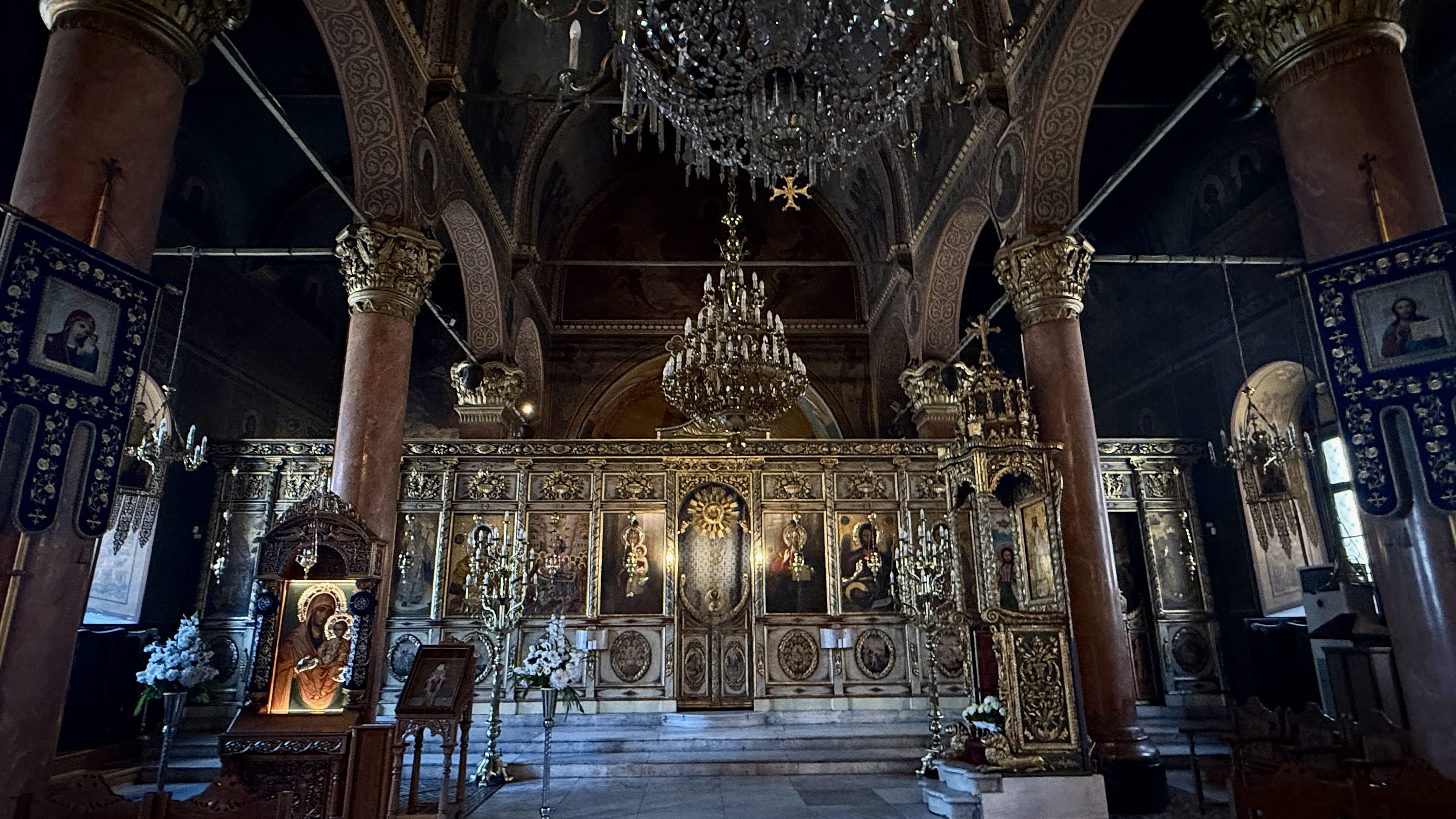 Ornate interior of the Church of the Holy Mother of God in Plovdiv, with its carved iconostasis, icons and chandeliers.