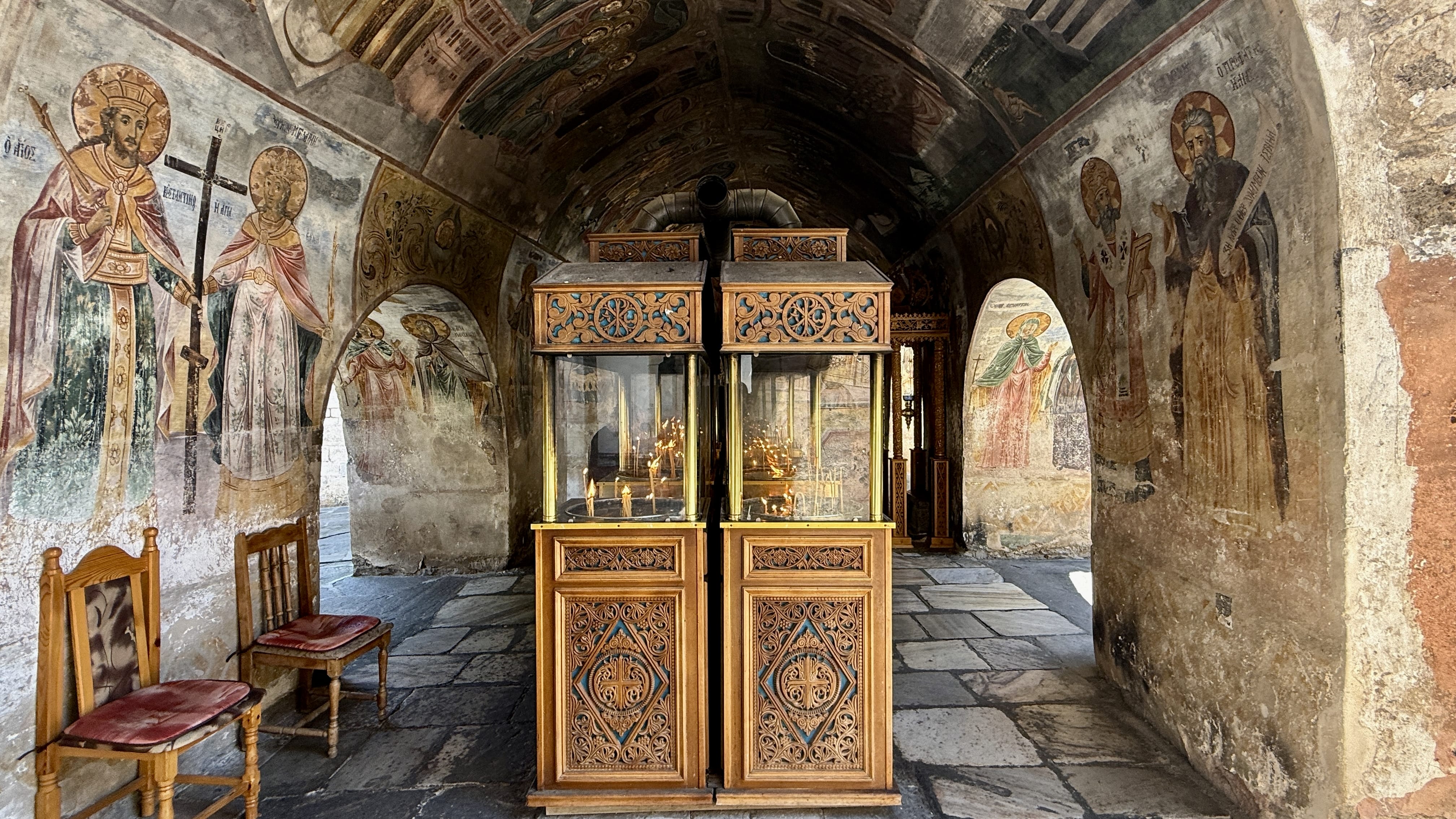 Fresco-covered interior of Bachkovo Monastery with wooden candle stands used by worshippers