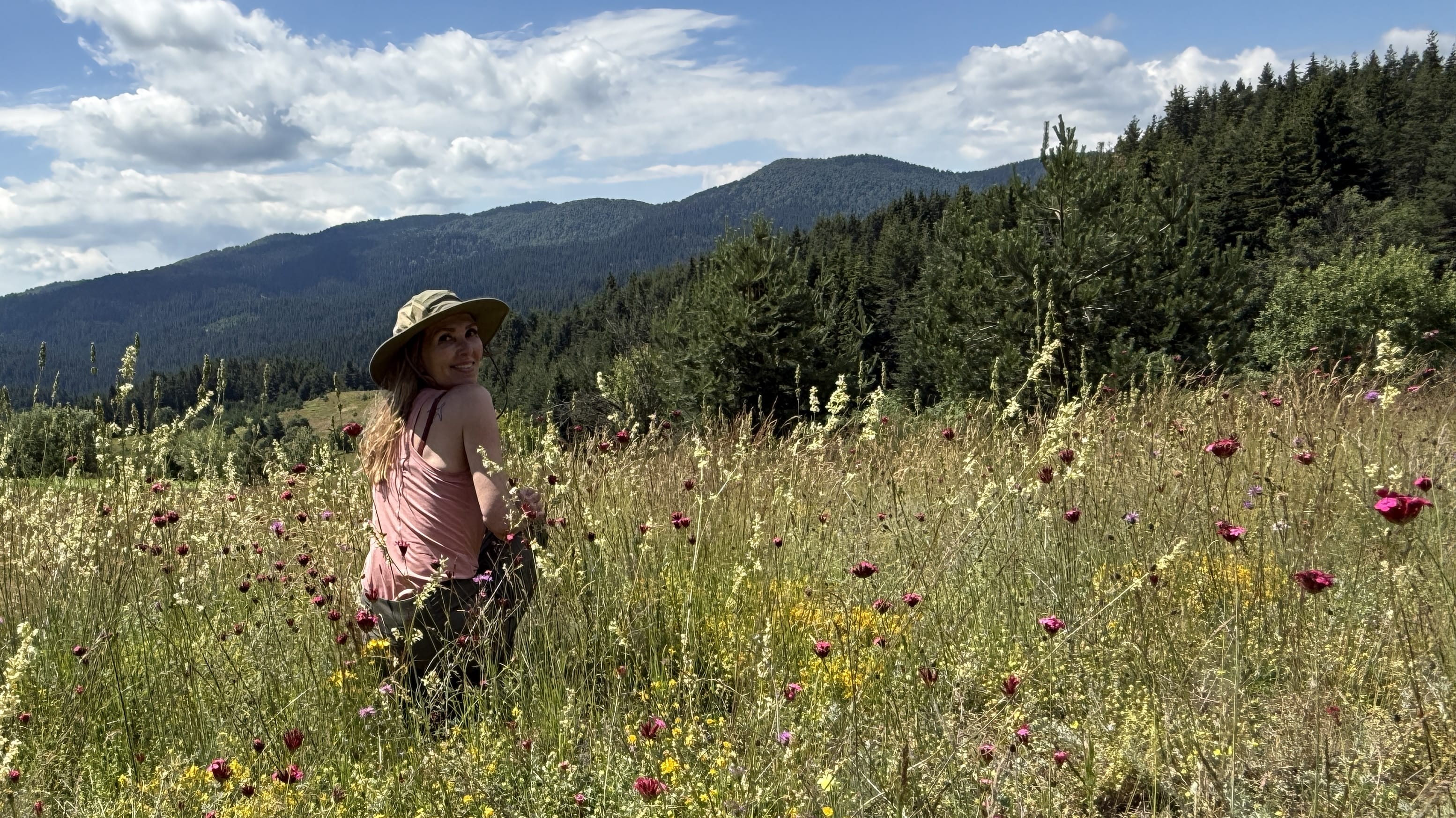 Woman hiking through a wildflower meadow in Bulgaria’s Rhodope Mountains